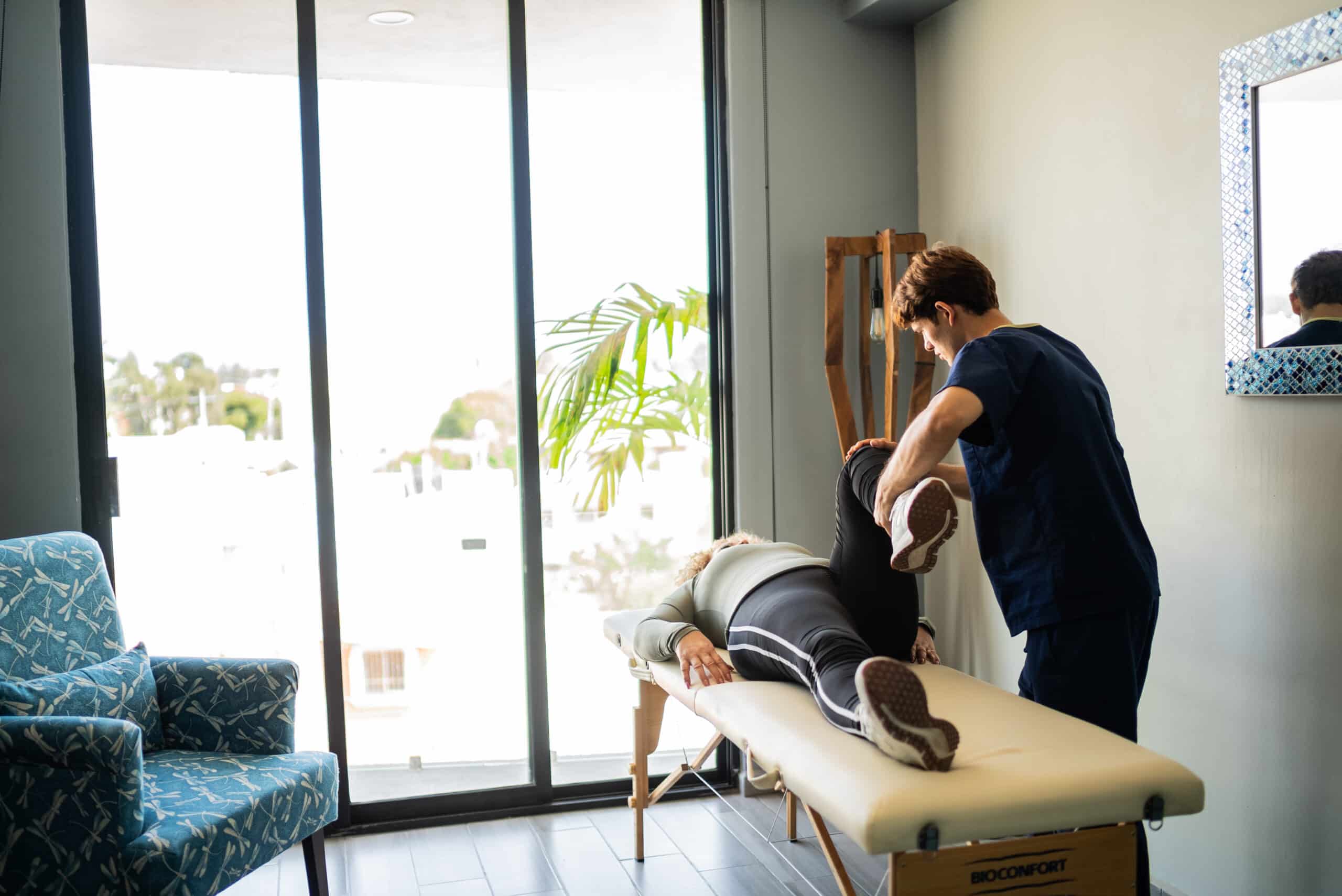 Giovane fisioterapista esegue esercizi di stretching per paziente anziano in casa a Torino